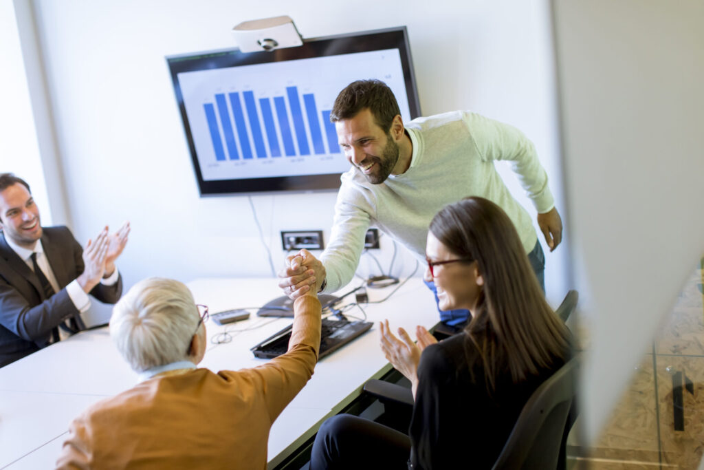 Profissionais em reunião comemorando resultados e planejando estratégias para antecipar recebíveis e fortalecer o fluxo de caixa